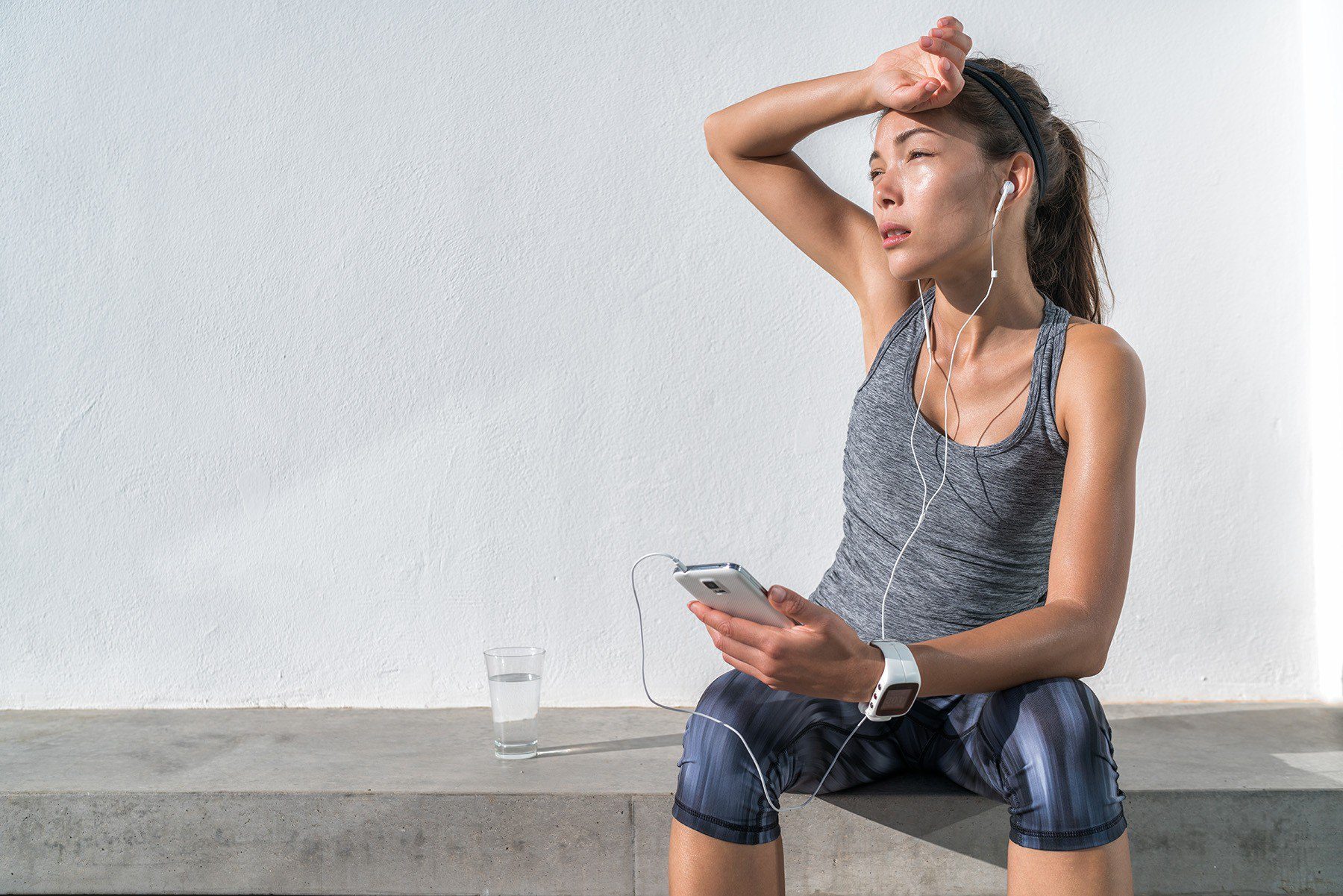 Woman in workout clothing sitting on a bench squinting off into the distance